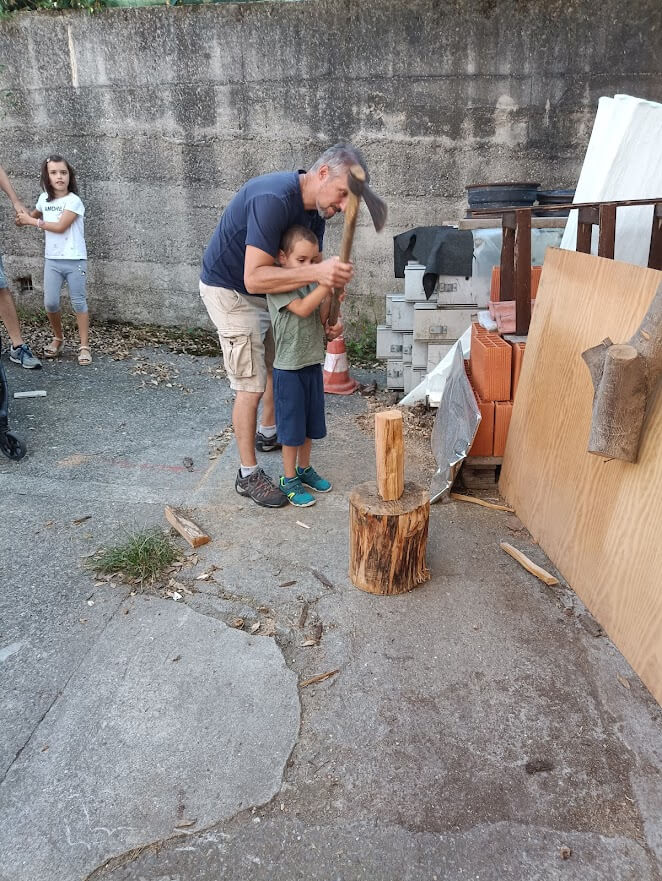 Adulto e bambino provano insieme a spaccare un pezzo di legno in uno spazio esterno.