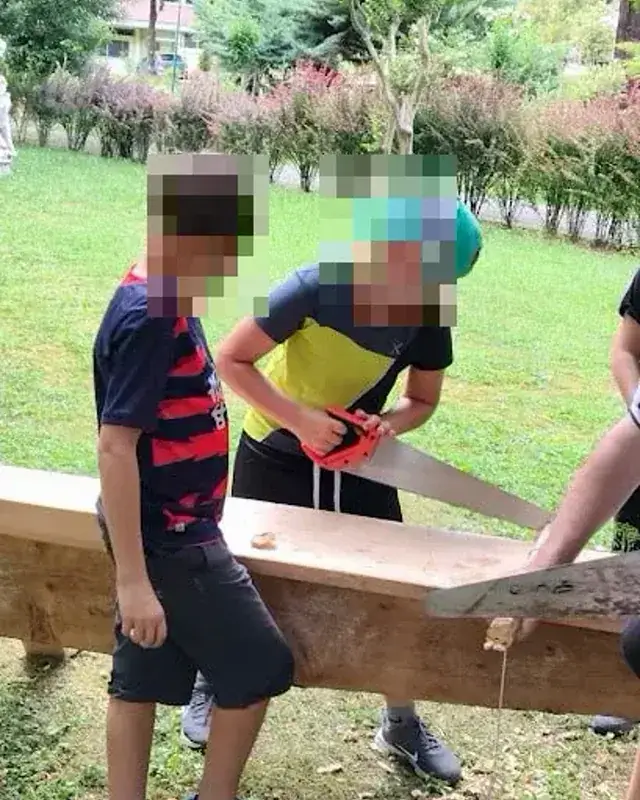 Due ragazzi provano una grande struttura di legno sul prato.