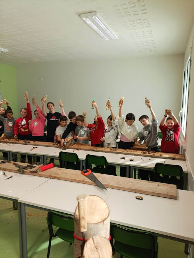 Ragazzo al lavoro su un banco da falegnameria mentre usa un utensile elettrico per rifinire un elemento in legno.